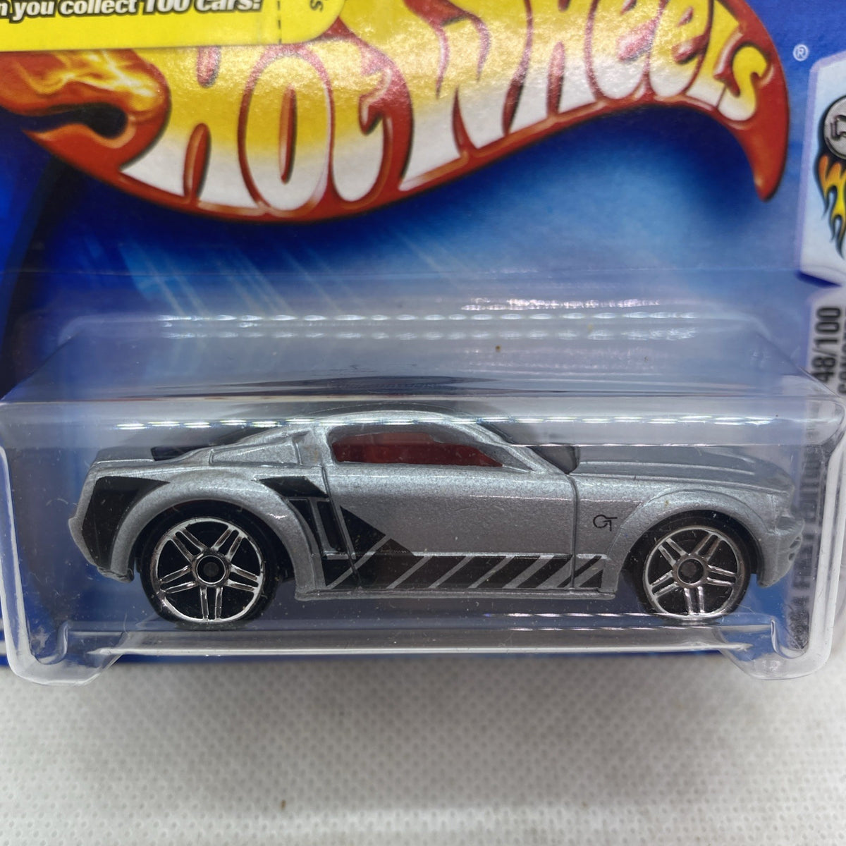 Hot Wheels die-cast car close-up in clear blister, silver/gray with black stripe and wheels