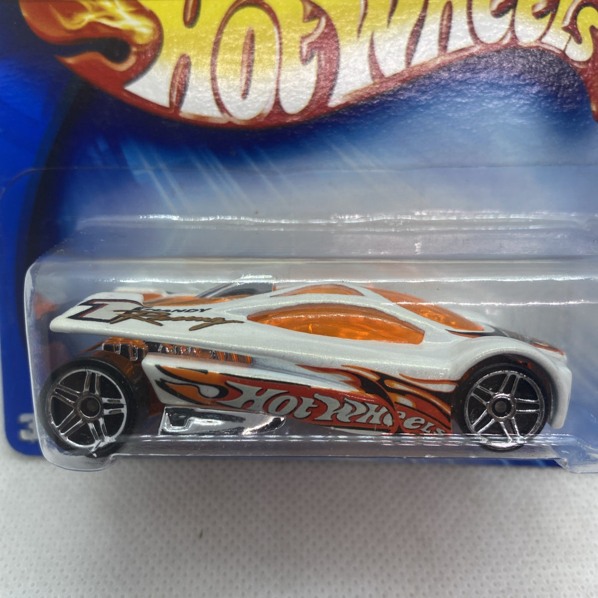 Close-up of toy car in clear blister, white body with orange flame-style graphics
