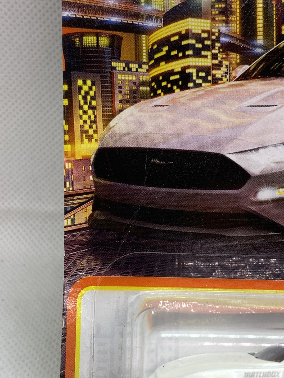 Close-up of toy car front end in Matchbox blister pack on orange card