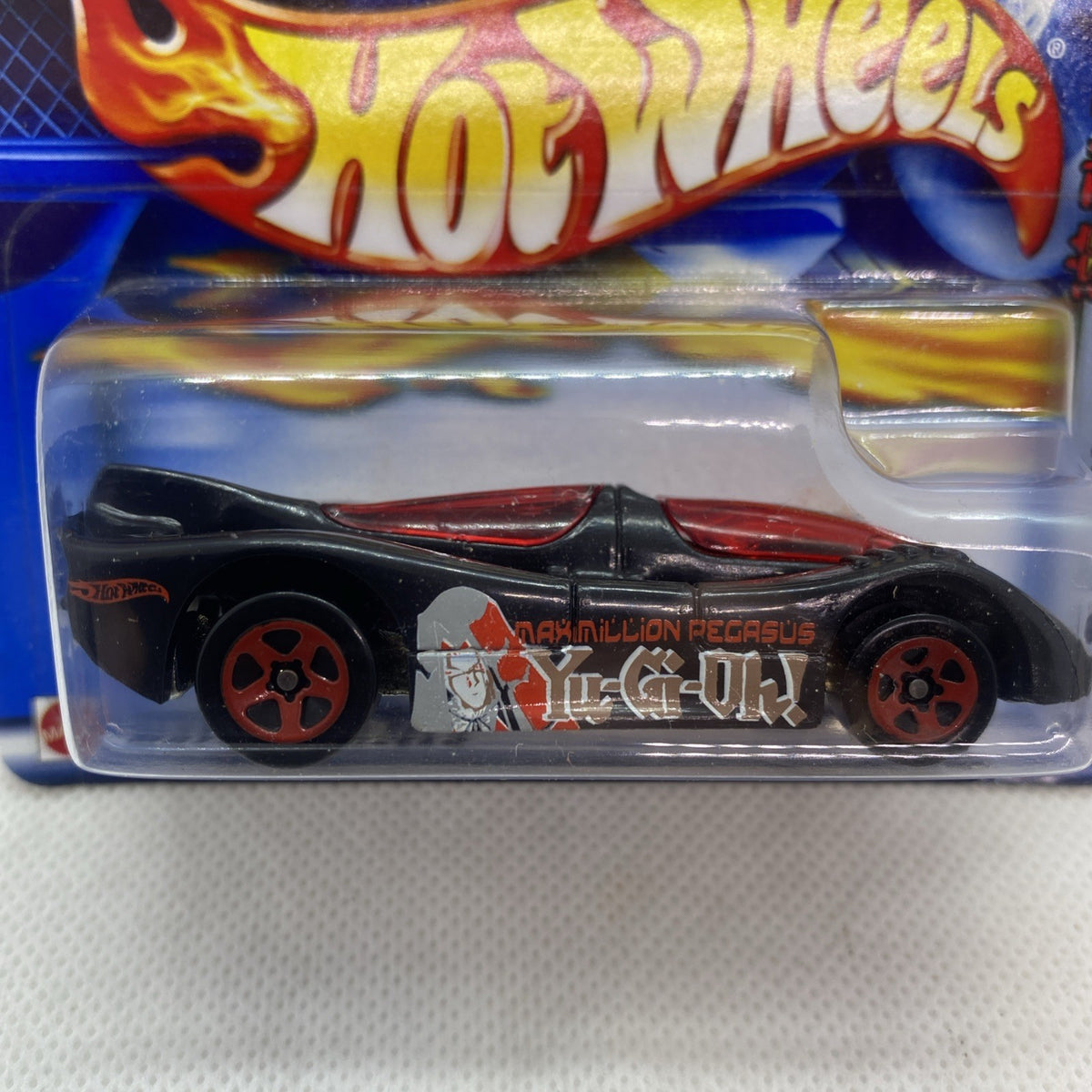 Close-up of Hot Wheels black and red car in clear blister, branding visible.