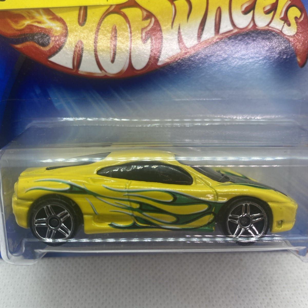 Close-up of yellow die-cast race car with green flame stripes in clear blister