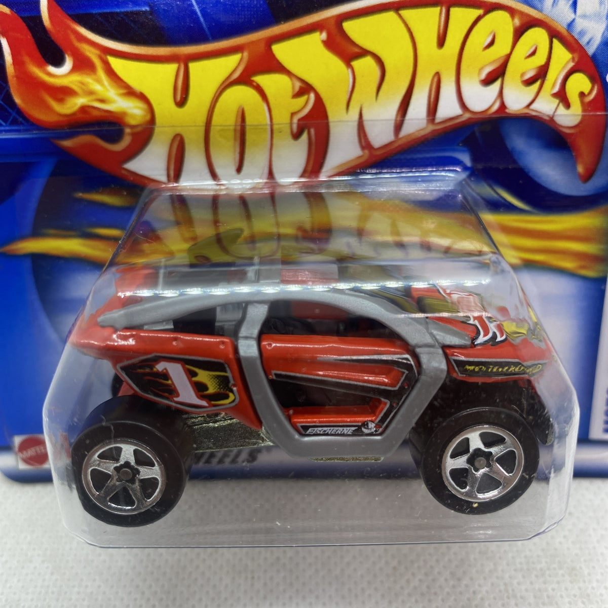 Hot Wheels die-cast motocross car close-up in clear blister, orange and black body