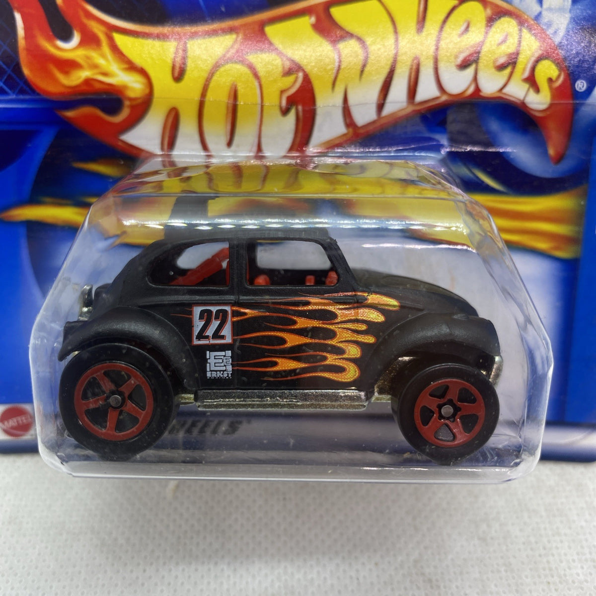 Die-cast toy car in blister pack, black body with orange flame decals and red wheel rims.