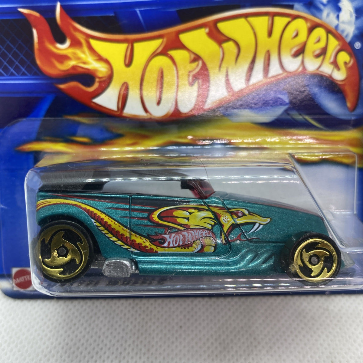 Close-up of Hot Wheels teal die-cast car with gold flame graphics in clear blister