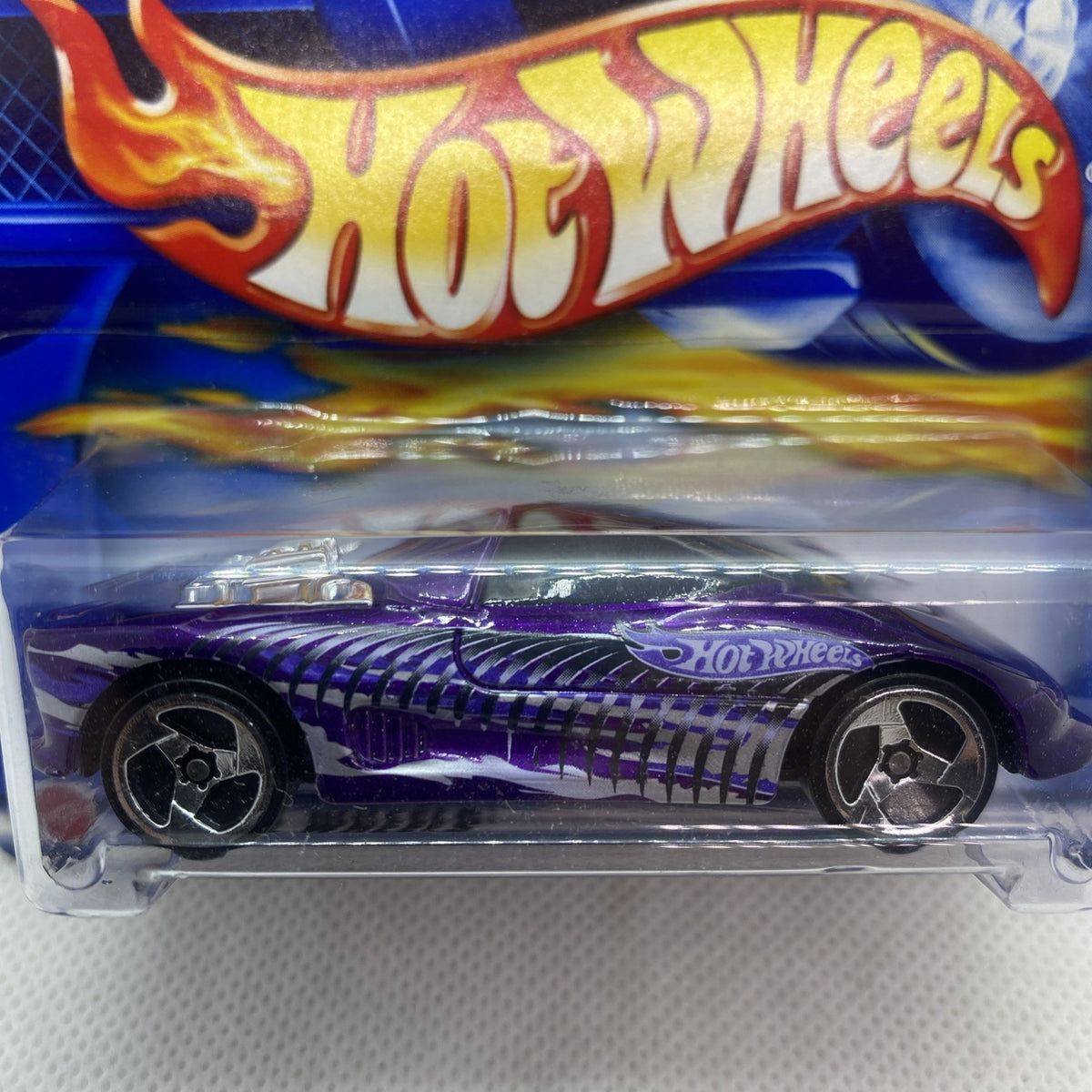 Close-up Hot Wheels die-cast car in purple, flame stripe hood and detailed wheels