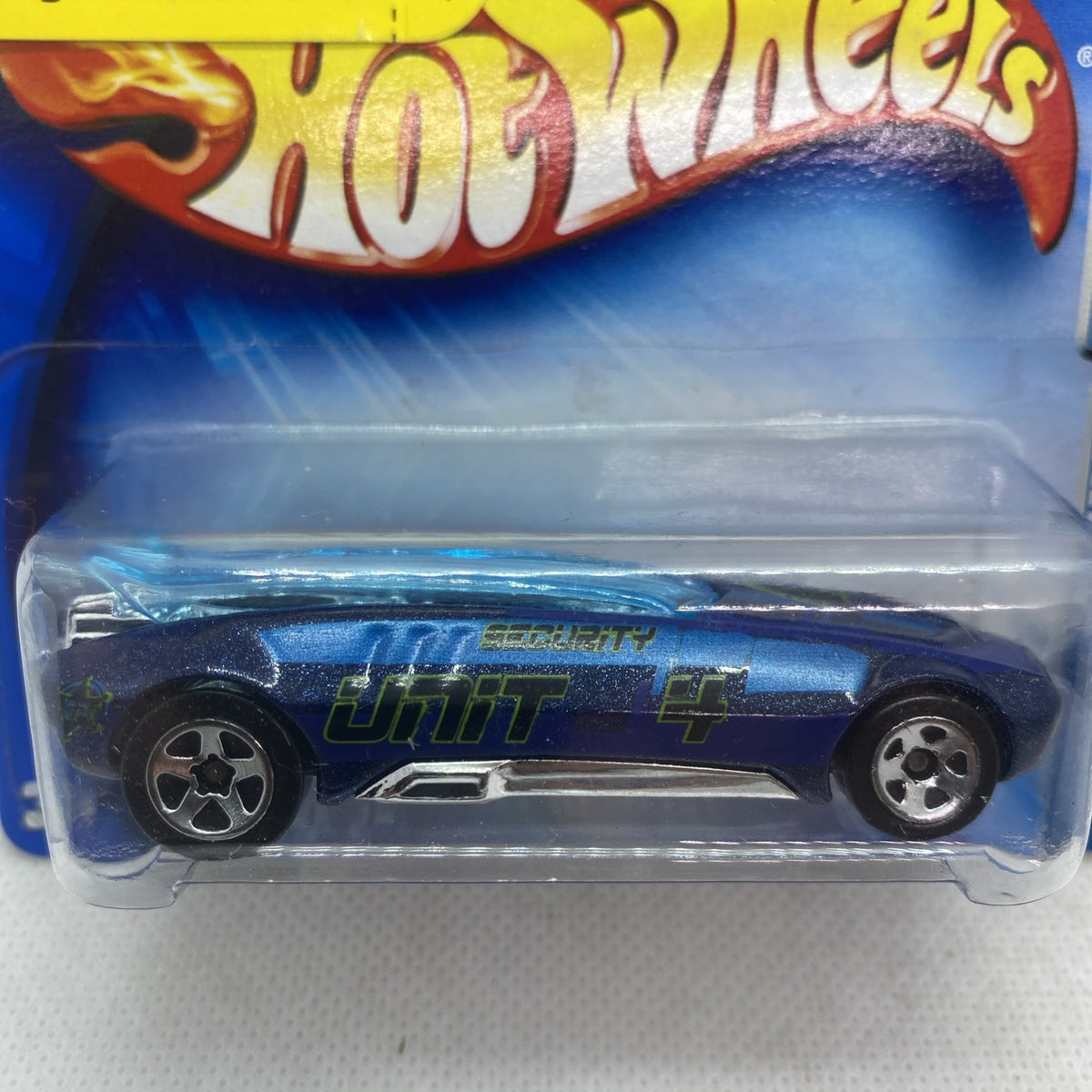 Blue Hot Wheels car in blister, side graphic and “UNIT” text visible, close-up