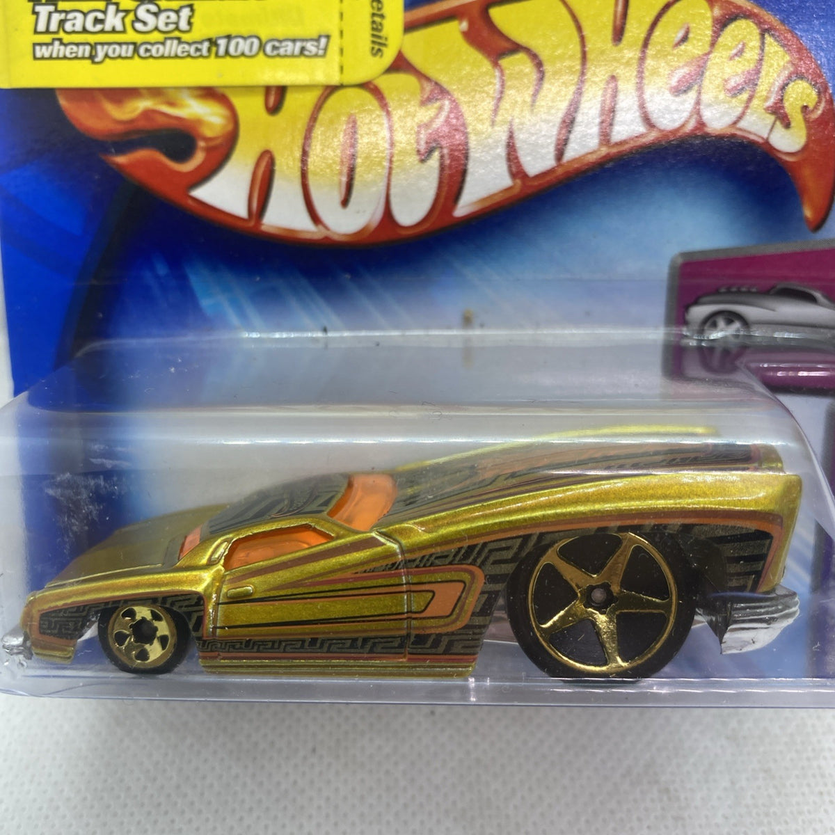 Hot Wheels die-cast car close-up in blister, yellow-gold body with star-rim wheels