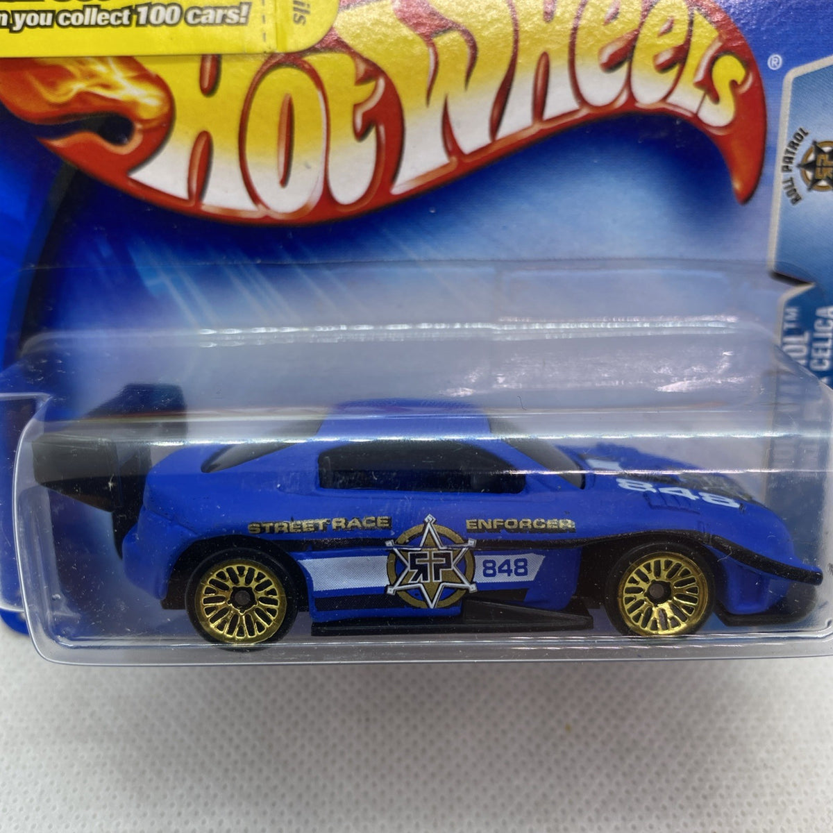 Hot Wheels blue race car with gold wheels in clear blister package close-up