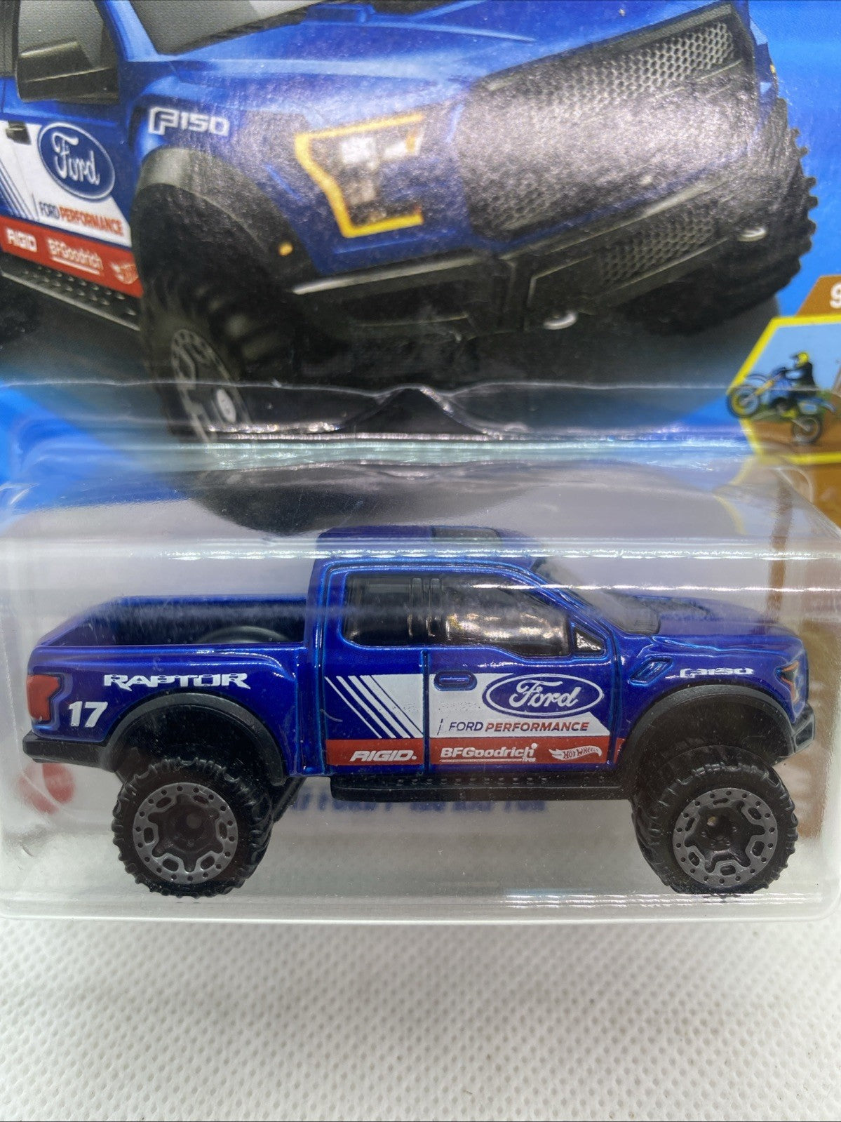 Blue '17 Ford F-150 Raptor Hot Wheels toy truck with off-road tires in blister