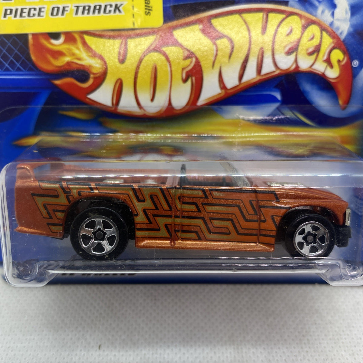 Orange Hot Wheels mini truck with black pattern and silver wheels in blister