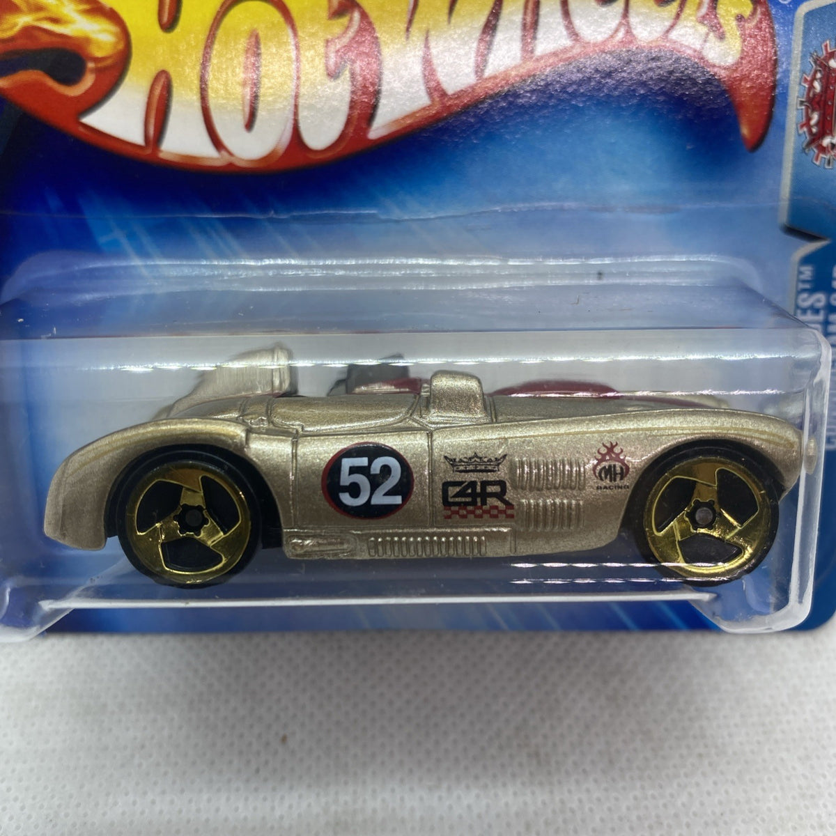 Gold die-cast race car in clear blister, black wheels and red accents