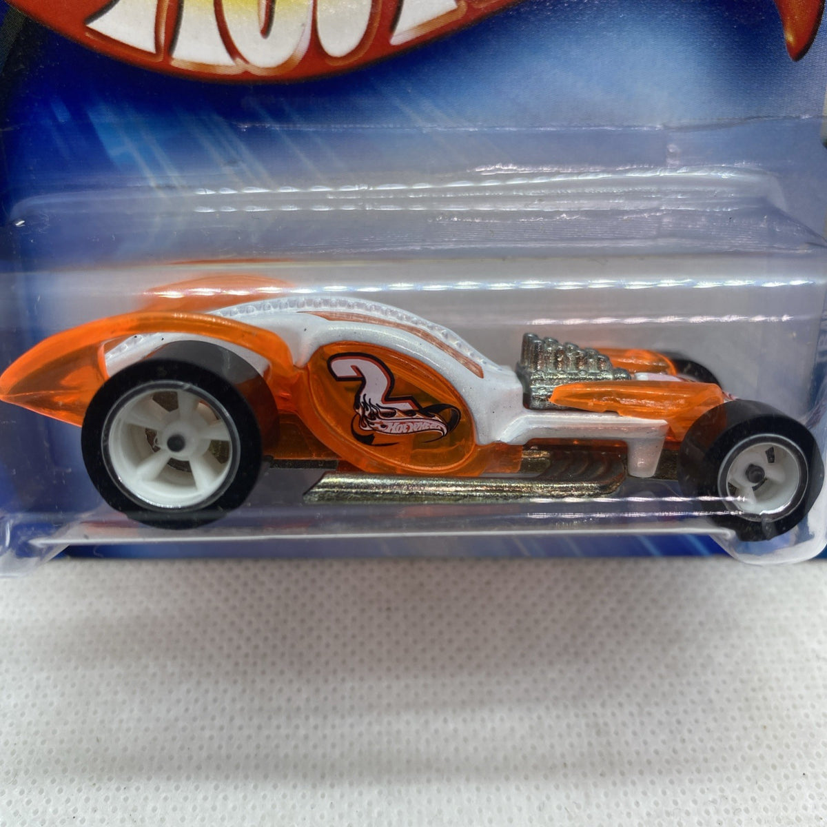 Hot Wheels orange and white race car toy close-up in clear blister