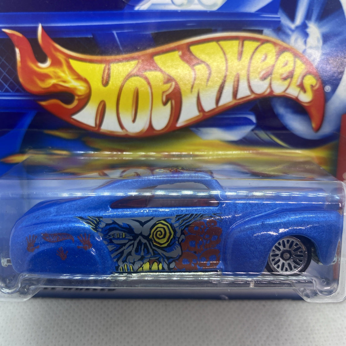 Hot Wheels blue tail-dragger die-cast car close-up with colorful monster graphic and flame logo.