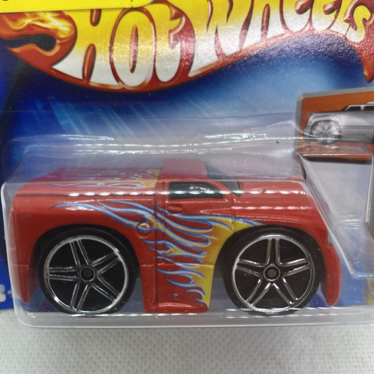 Hot Wheels Dodge Ram 2004 die-cast pickup close-up: orange flame body and chrome wheels