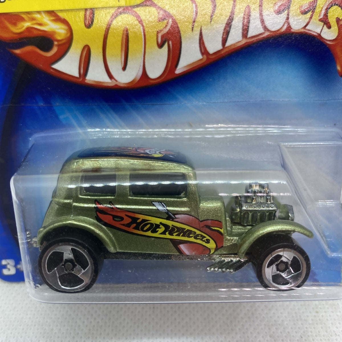 Hot Wheels die-cast green car close-up in clear blister pack, side view