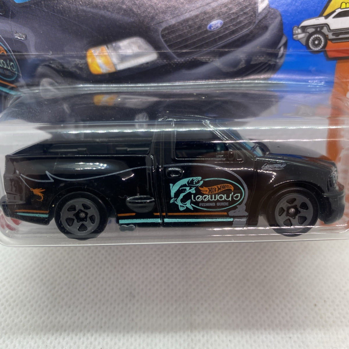 Hot Wheels black pickup toy close-up in blister, teal door logo and orange stripe graphics.