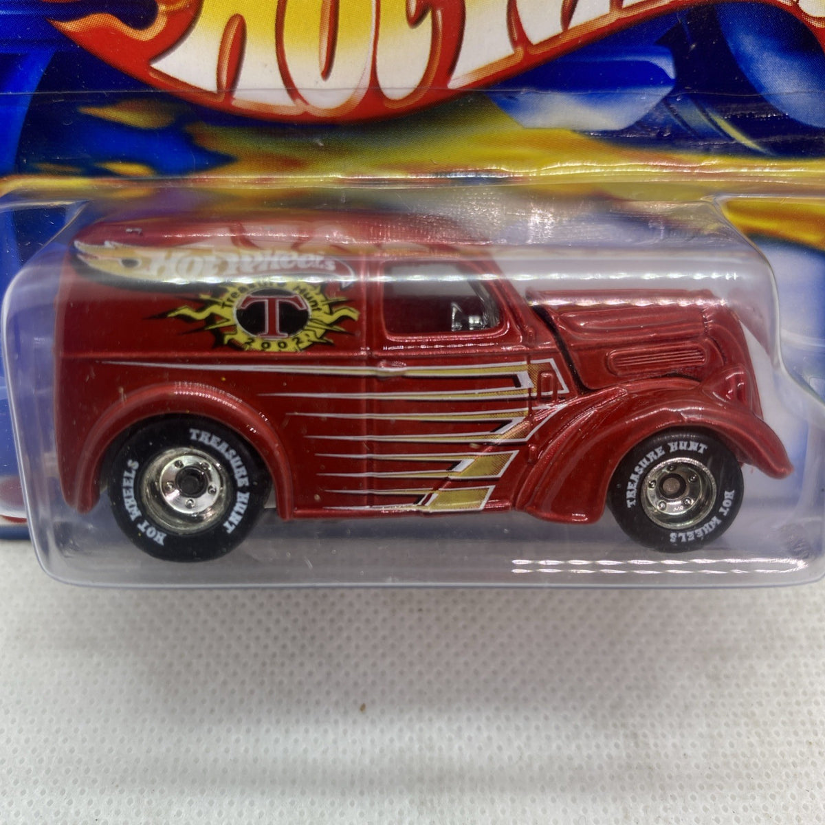 Close-up of Hot Wheels red panel van toy car with gold stripes and front decals