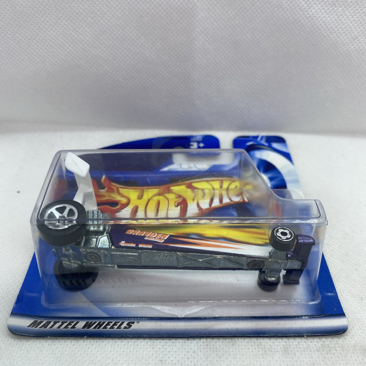 Die-cast dragster in clear blister with flame graphics and black wheels on blue card.