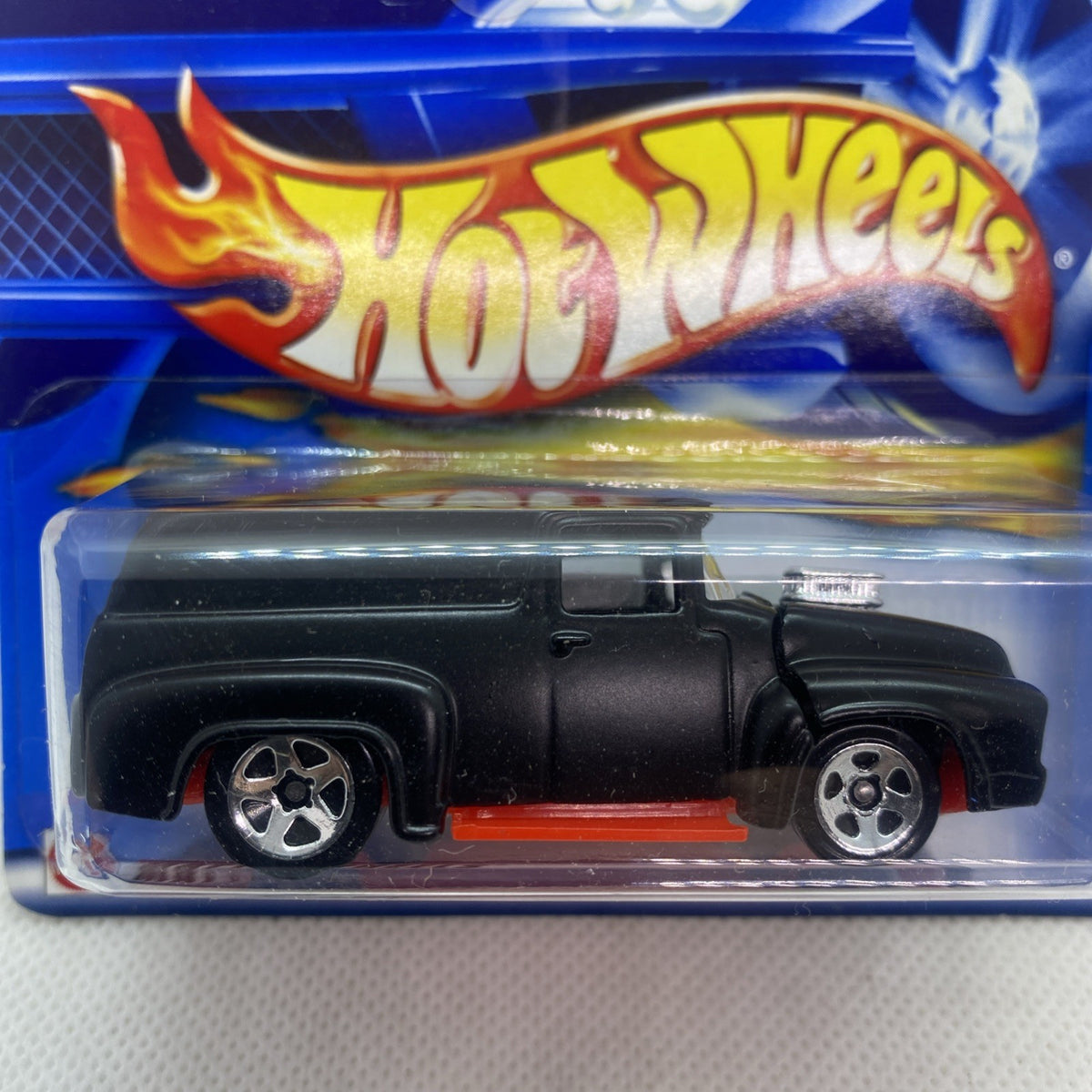 Hot Wheels die-cast truck close-up in blister, black body, red stripe, flame-themed graphics