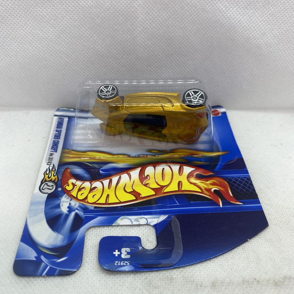 Hot Wheels gold die-cast car in clear blister on blue card, angled view