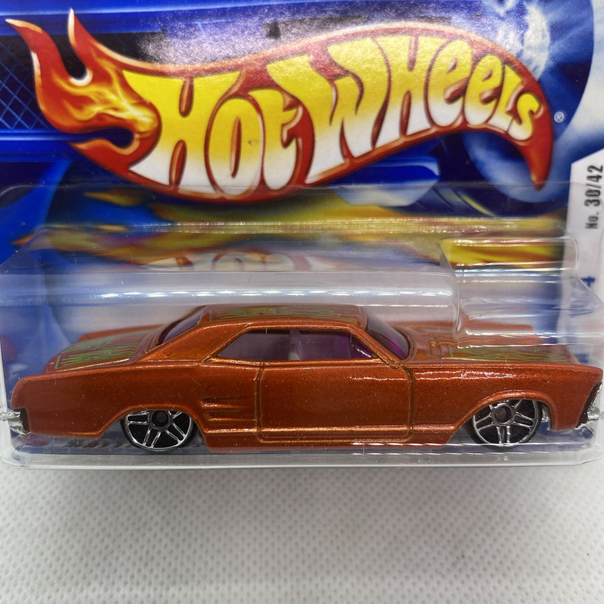 Orange die-cast car close-up in clear Hot Wheels blister pack, flame logo visible