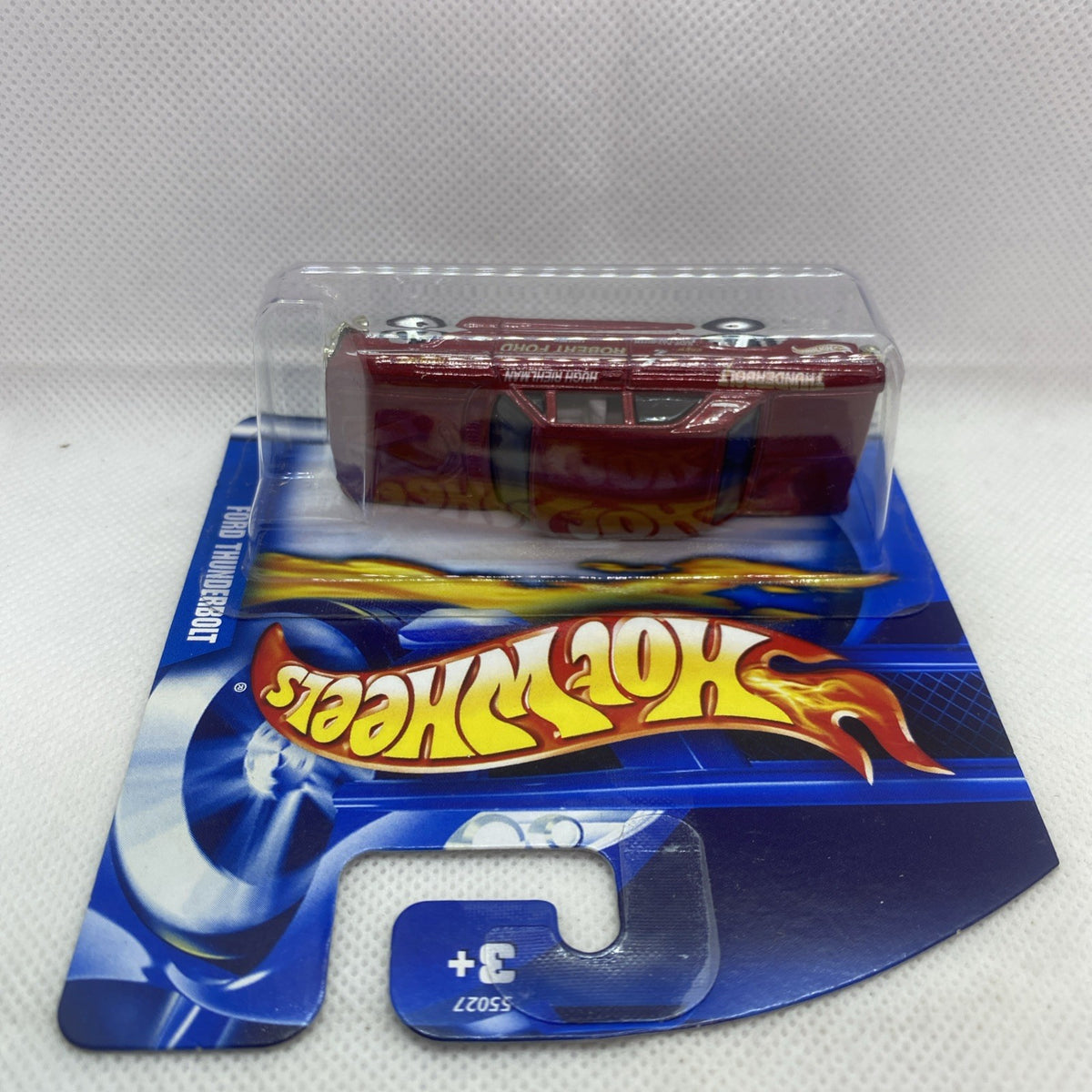 Hot Wheels die-cast car in clear blister, maroon body seen from above