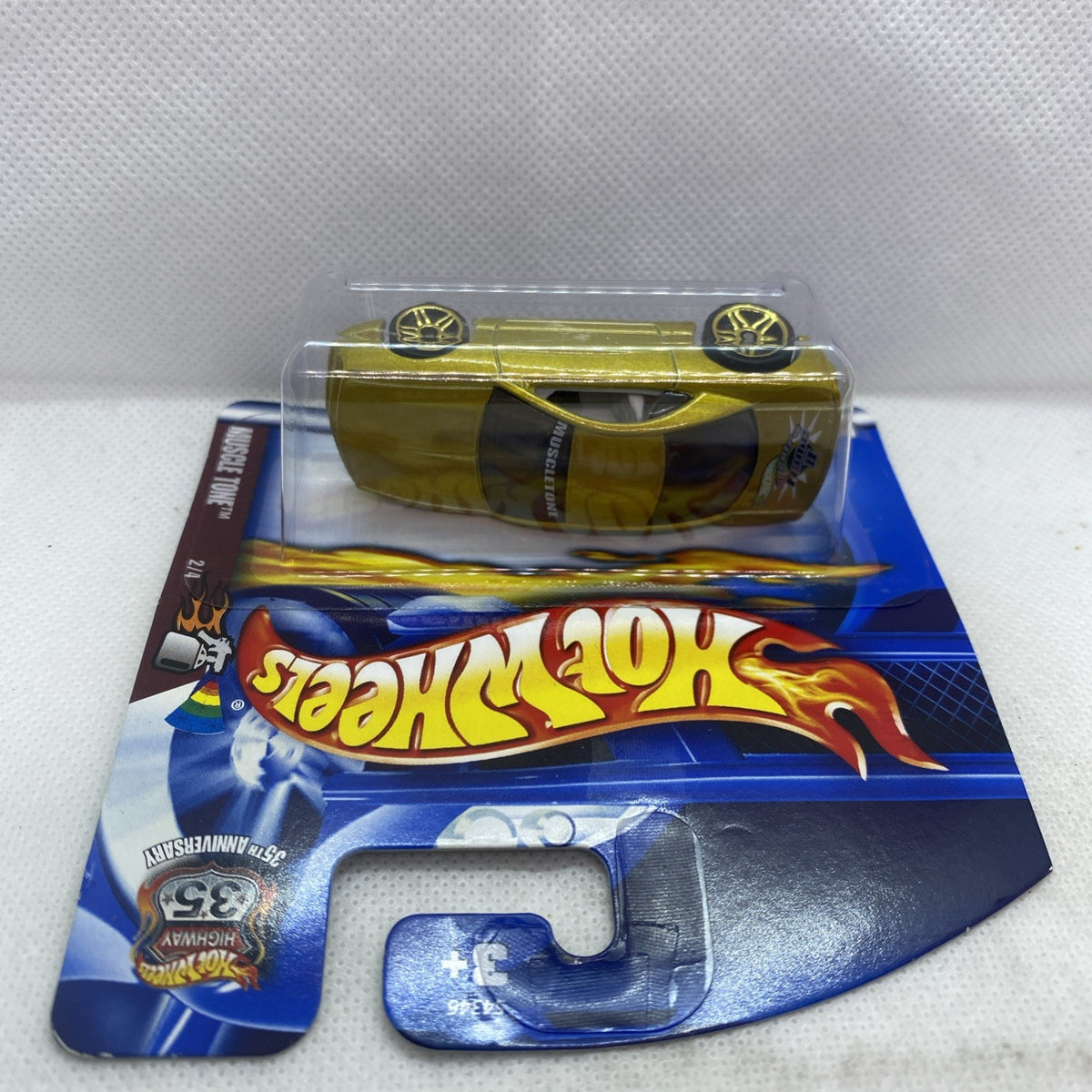 Hot Wheels muscle car toy on blue card, metallic yellow-green body under clear plastic