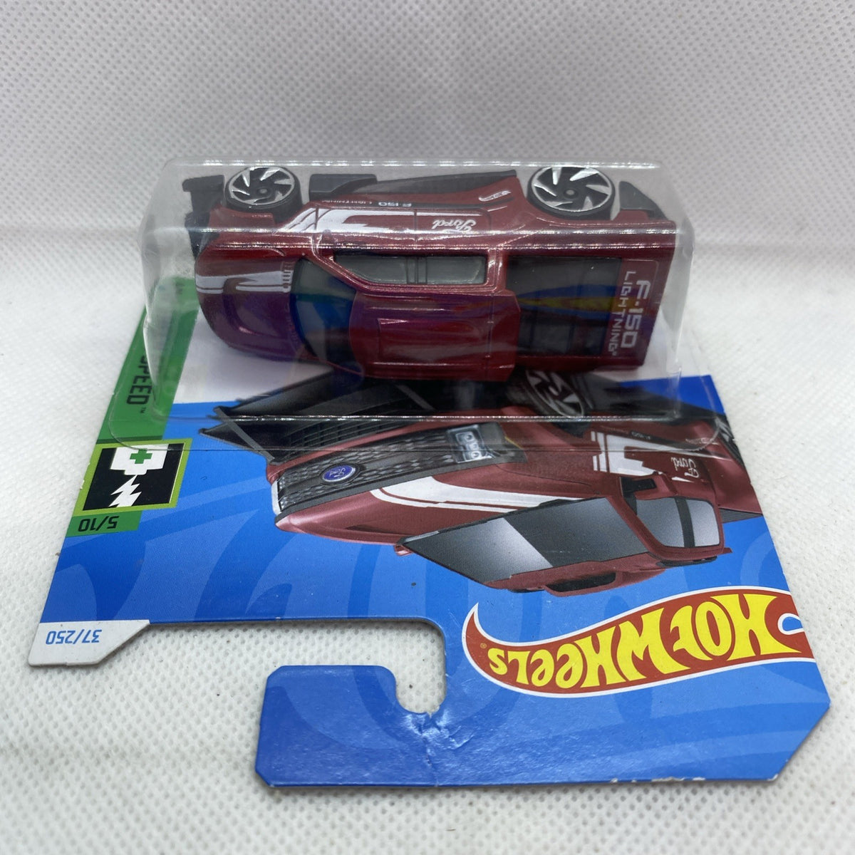 Maroon die-cast pickup truck toy in clear blister, angled top and side view