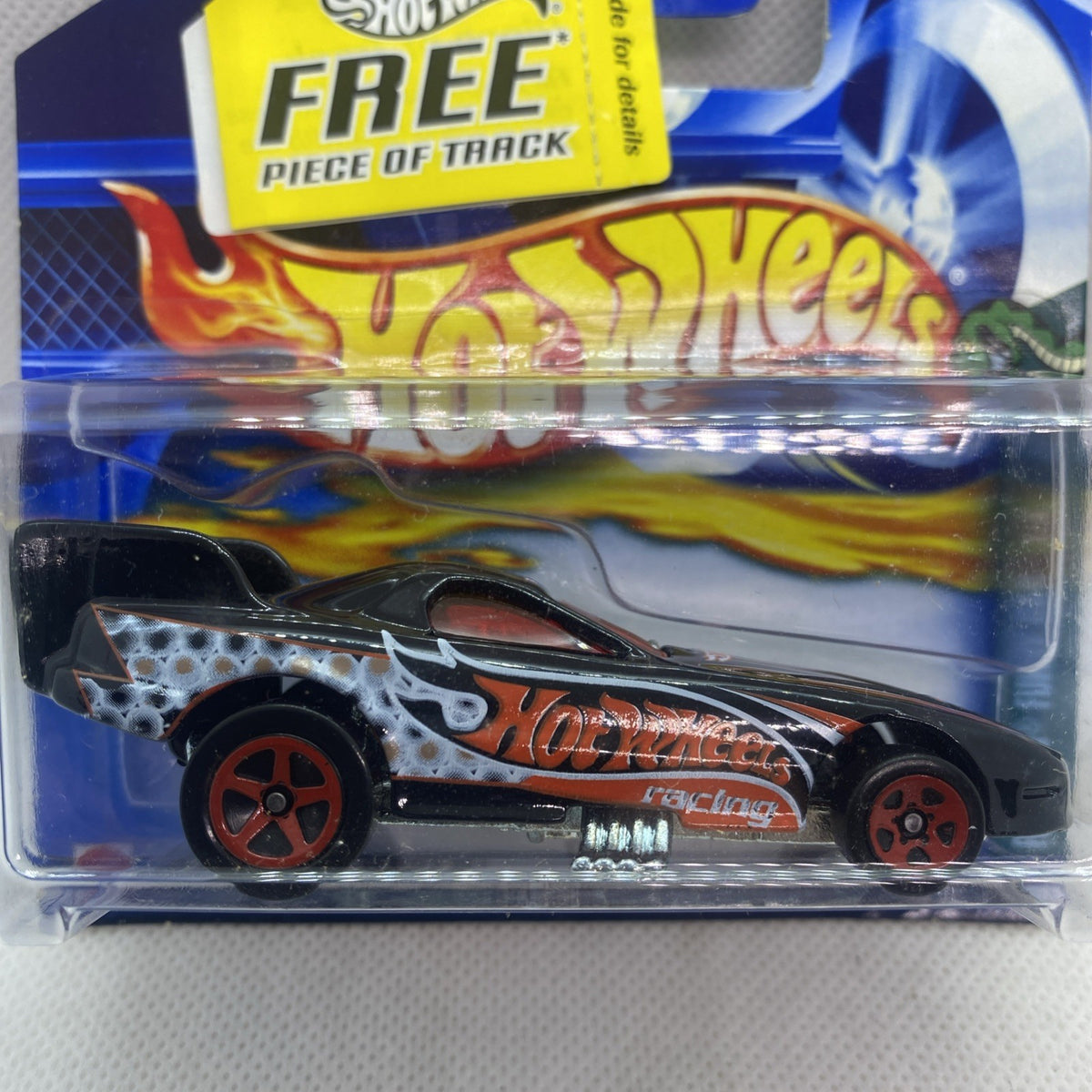 Hot Wheels Funny Car die-cast toy in clear blister, black body with orange flame decals.