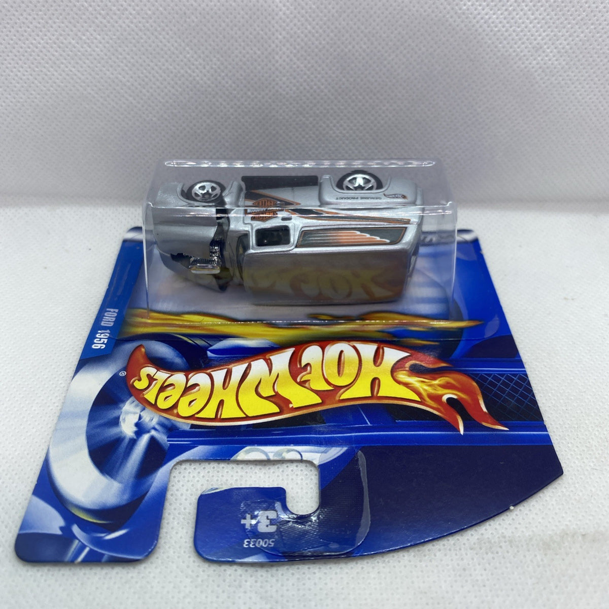 Hot Wheels blister pack from side view showing silver pickup truck with orange stripes
