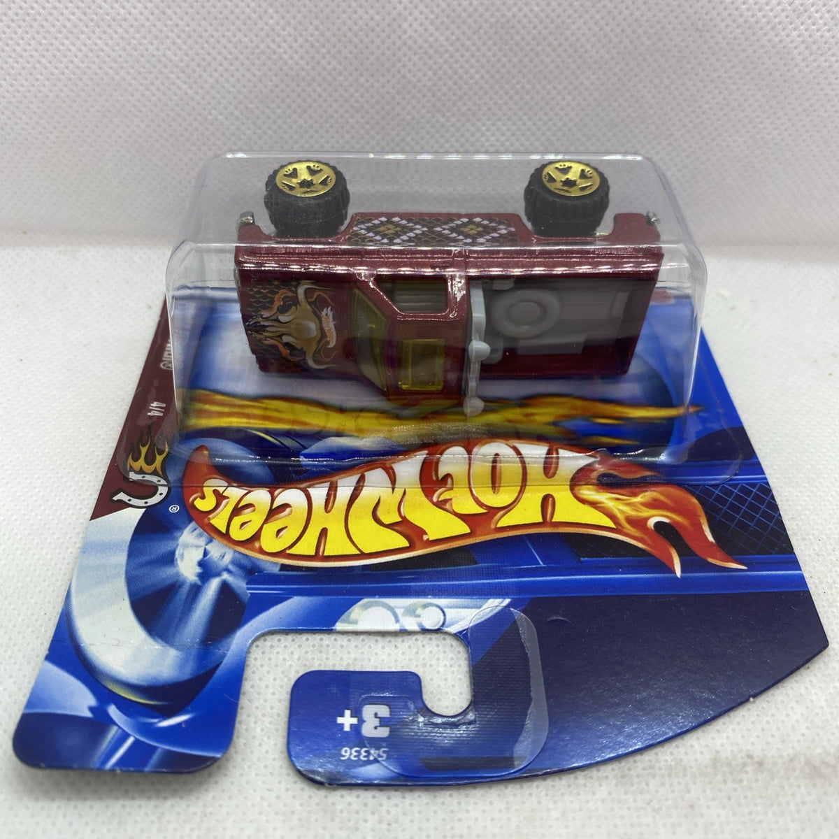 Hot Wheels die-cast pickup viewed from above in blister pack, maroon flames and yellow wheels