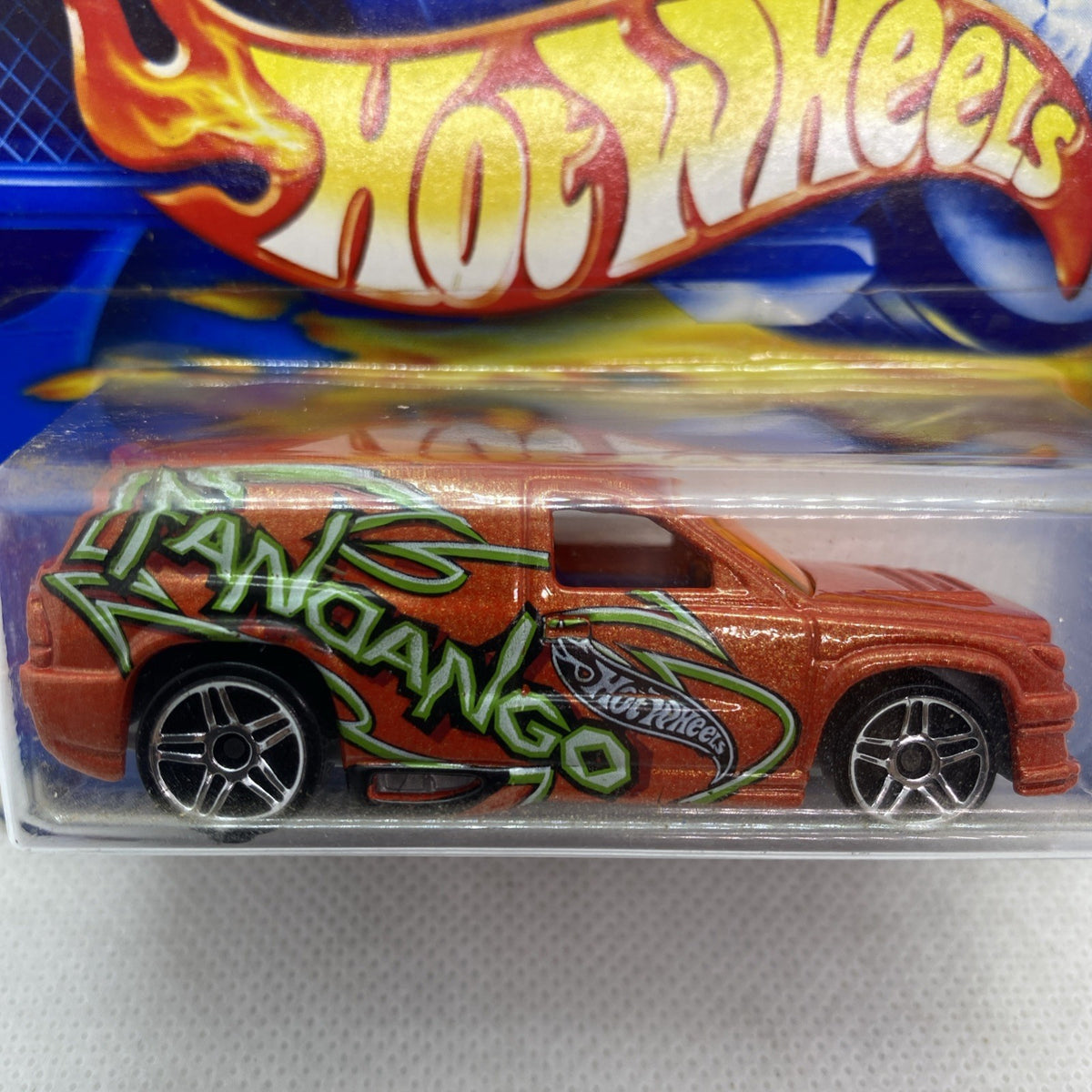 Hot Wheels die-cast car close-up, orange body with green graffiti flames and chrome wheels