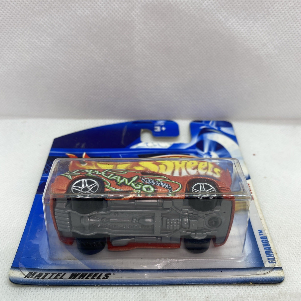 Hot Wheels blister card showing underside view of orange die-cast car with black wheels