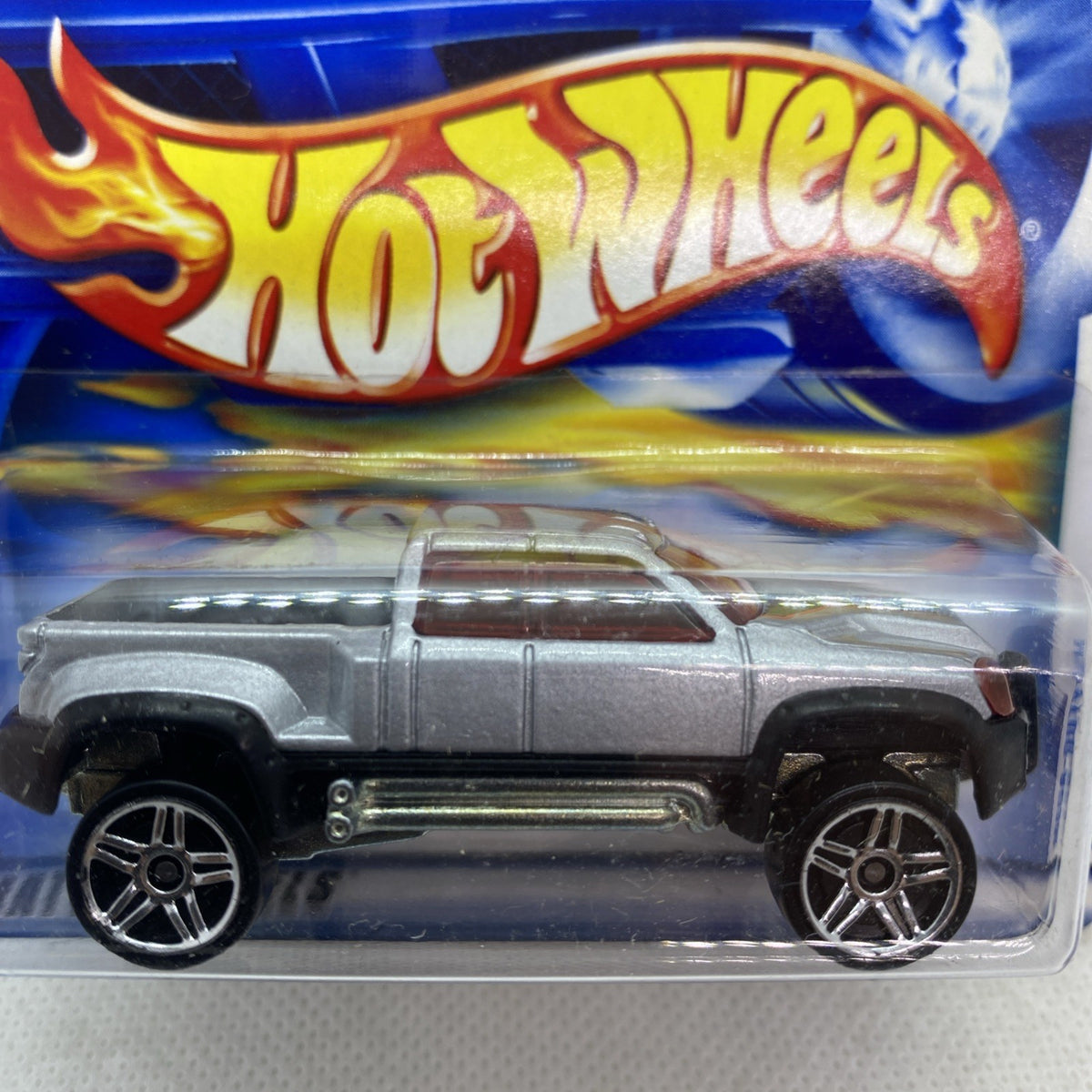 Silver die-cast pickup truck close-up with chrome detailing and black wheels in blister