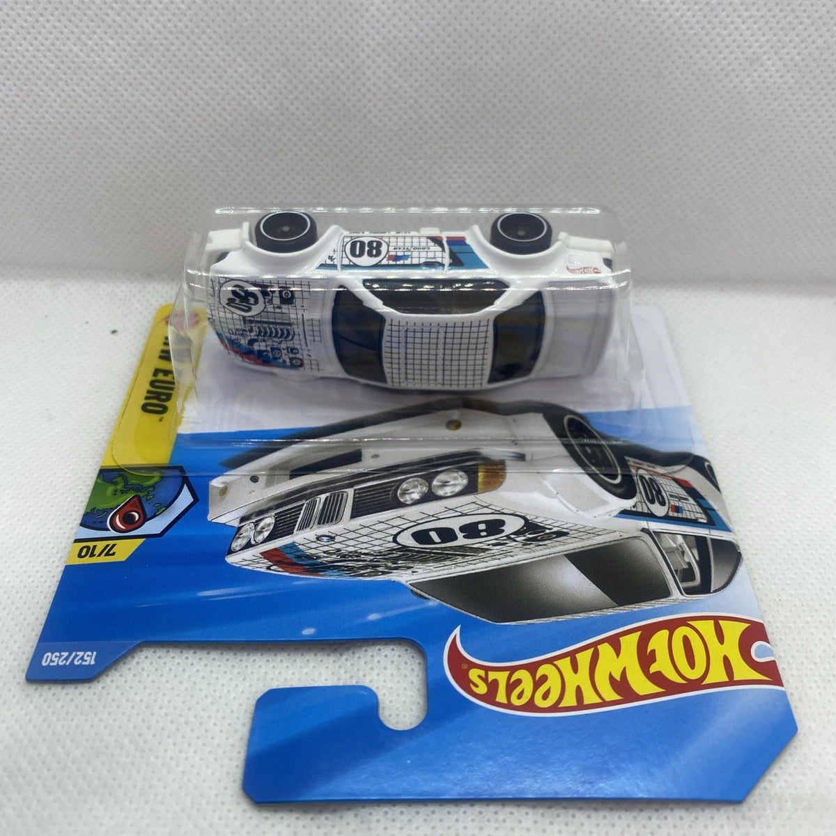White die-cast car in clear blister, top view with blue grid and number 08