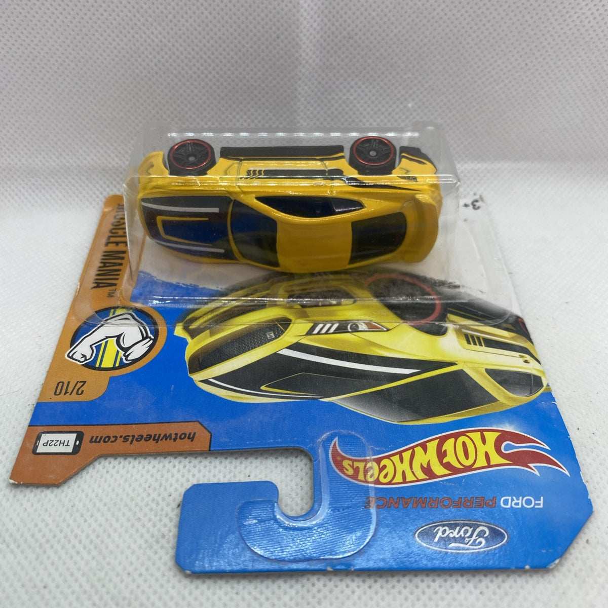 Yellow Hot Wheels muscle car blister, top-down view on blue card