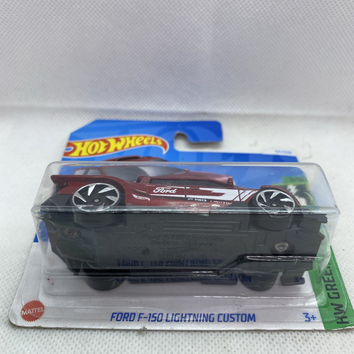 Maroon die-cast pickup truck toy in clear blister, side profile with Ford logo
