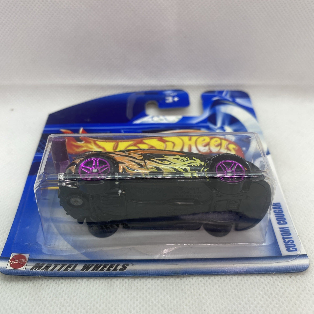 Hot Wheels die-cast car in clear blister packaging with black body and purple wheels