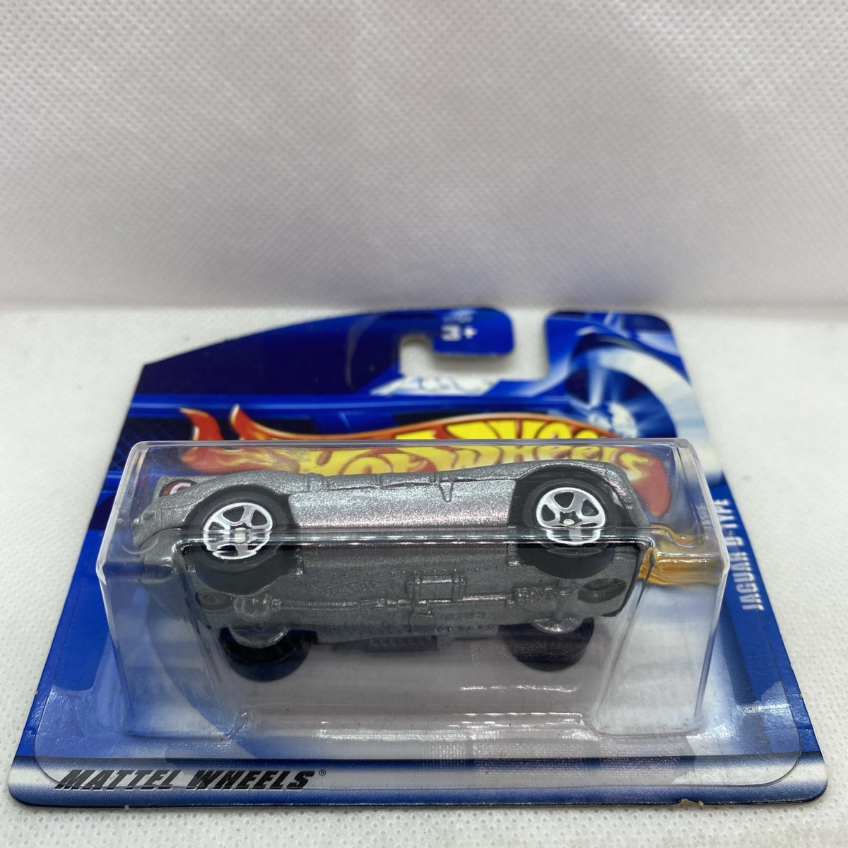 Hot Wheels Jaguar D-Type die-cast car in sealed blister, angled side view, silver