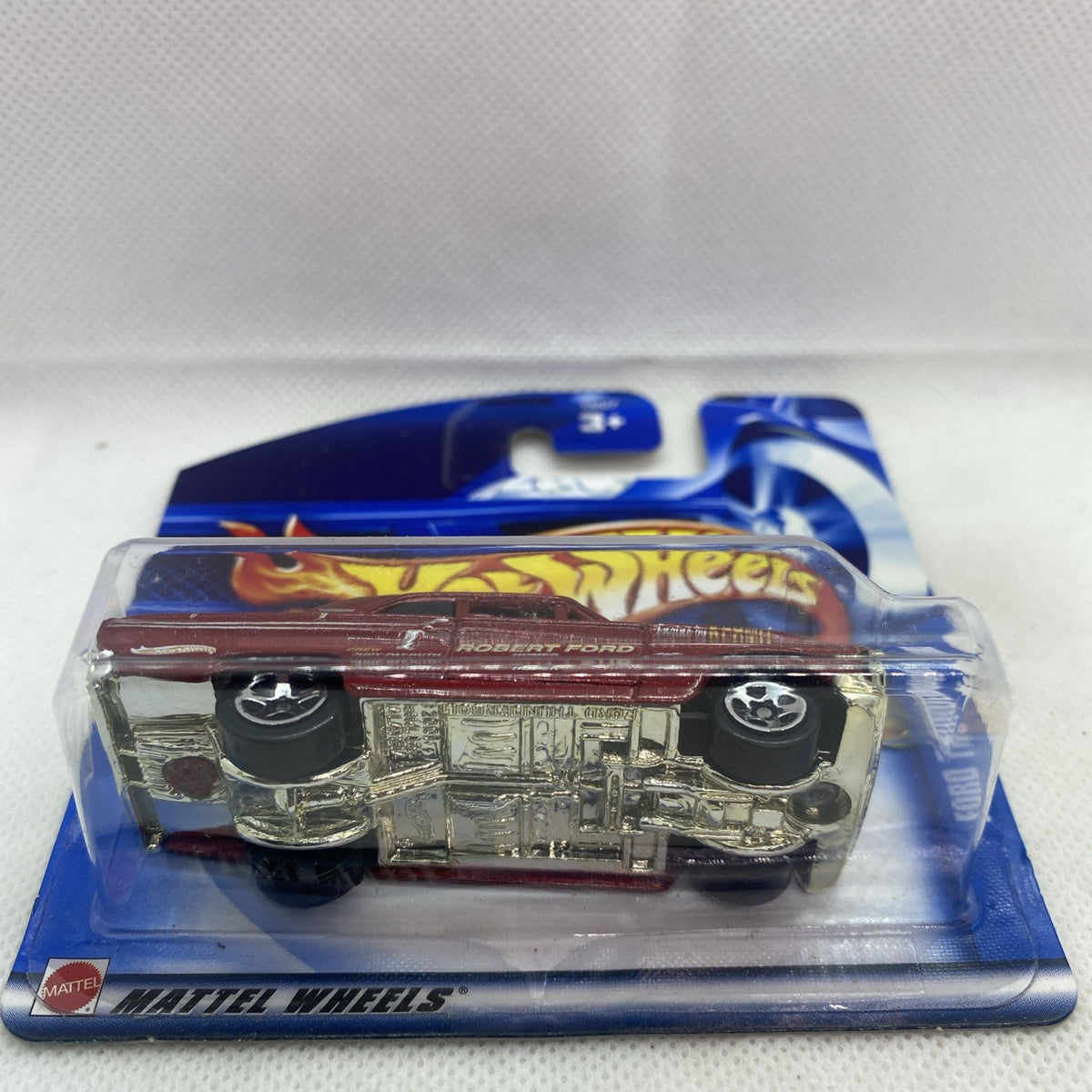 Hot Wheels die-cast car in blister pack, maroon body with silver underside detail