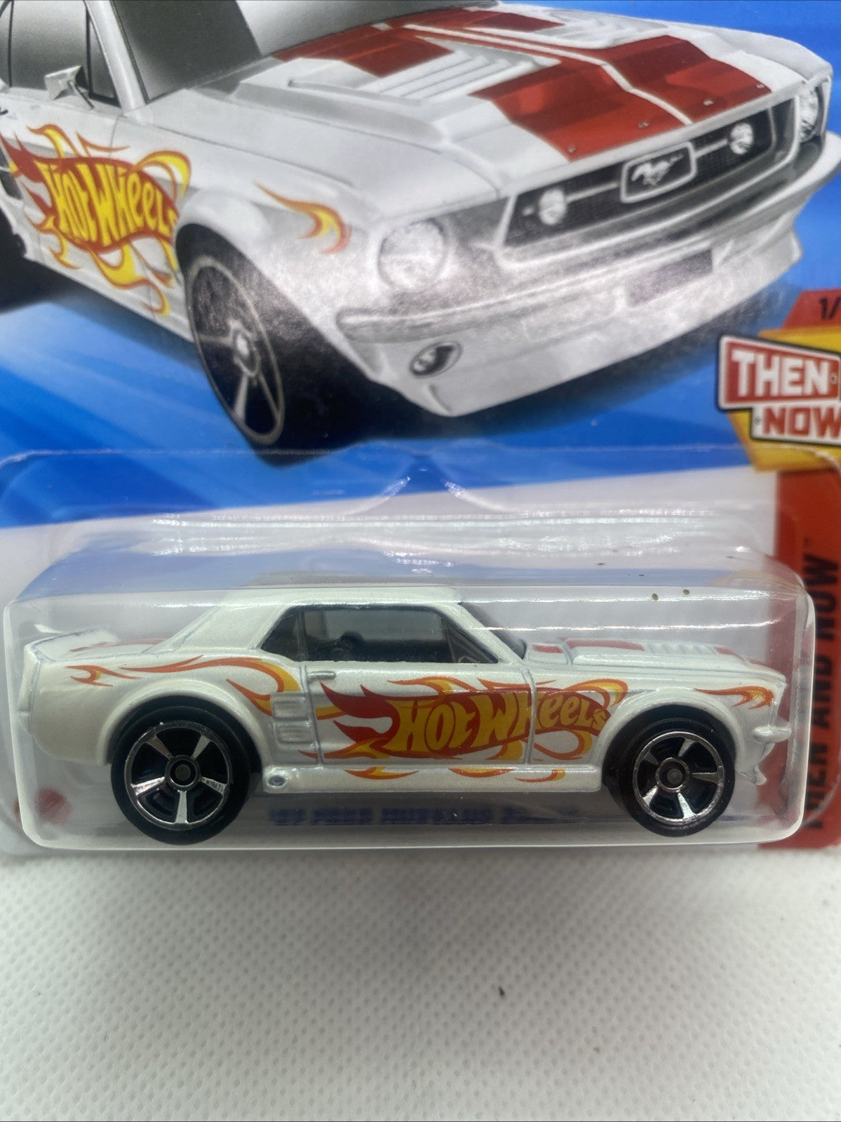Hot Wheels die-cast car in blister pack, side view with flame graphics and black wheels