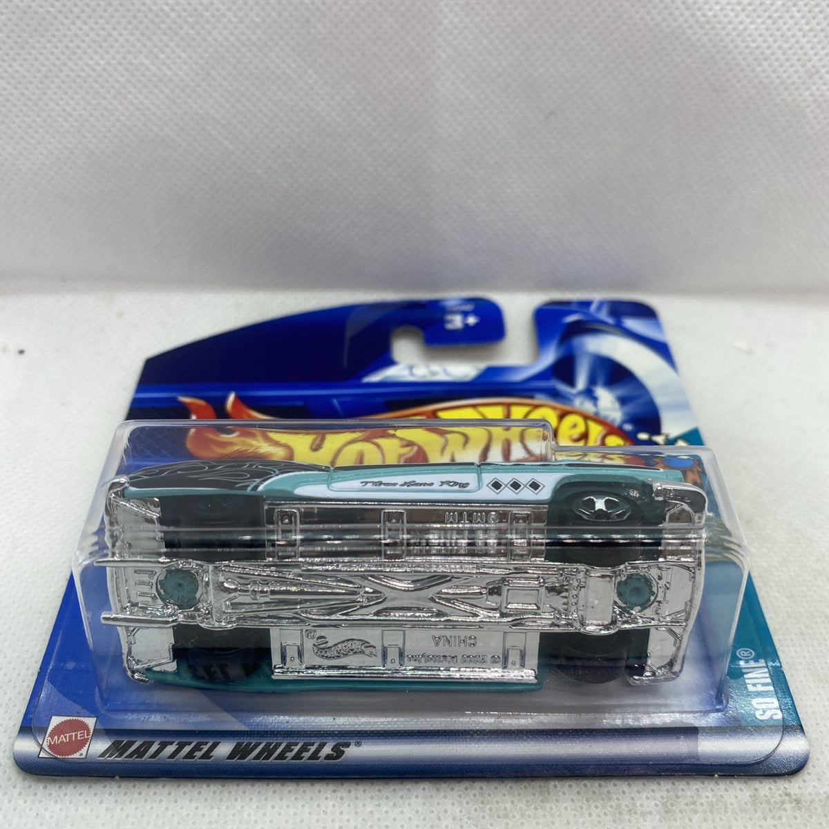 Bottom/side view of teal die-cast truck in clear blister on blue short card