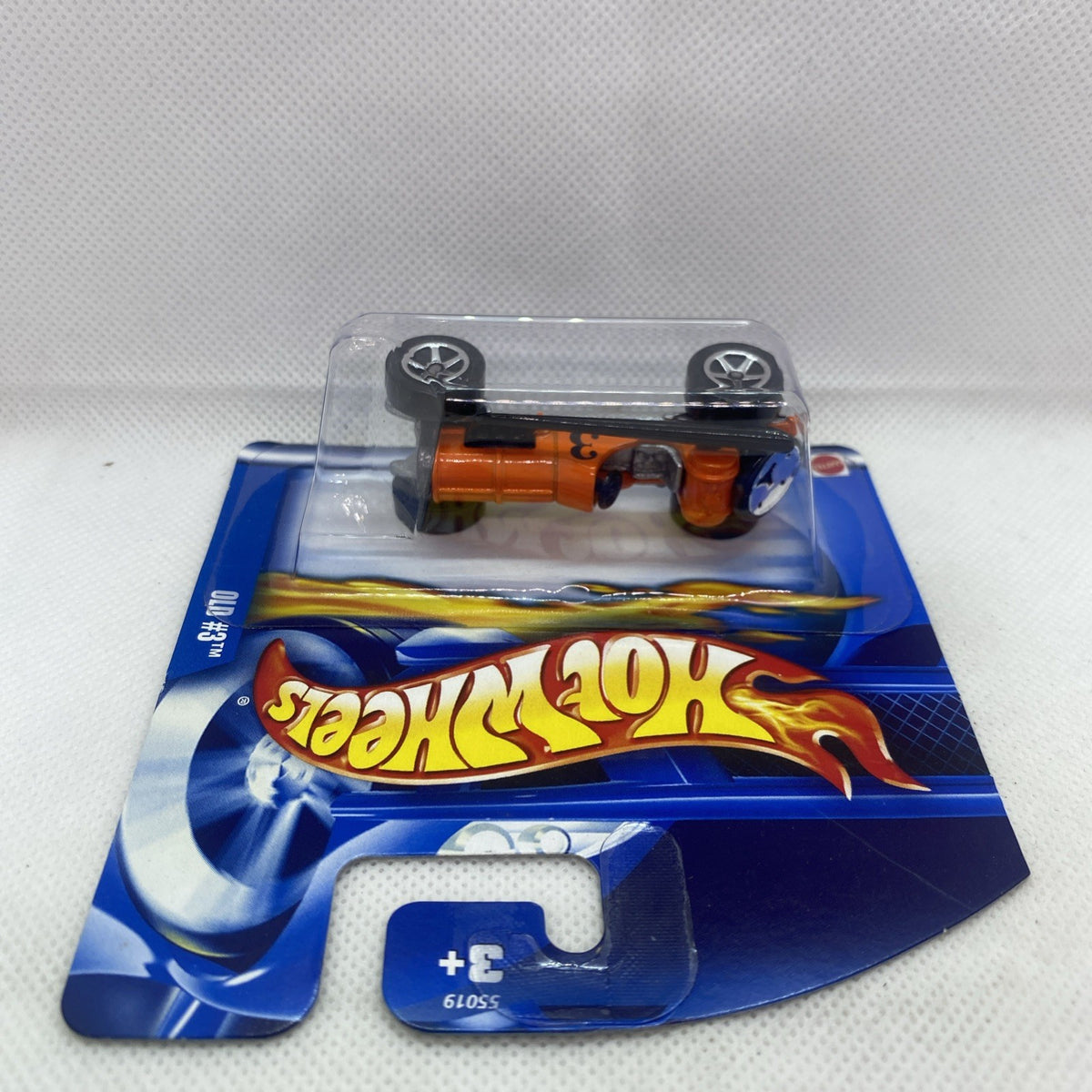 Hot Wheels orange die-cast car in clear blister on blue card, top view