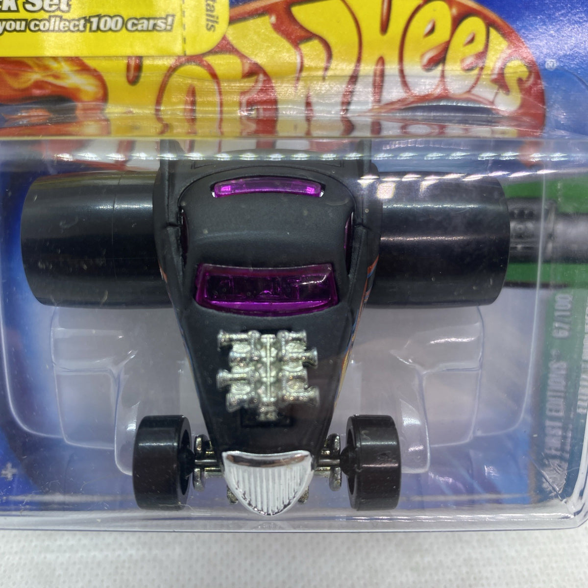 Hot Wheels die-cast car close-up in blister pack, black with purple window and silver grille