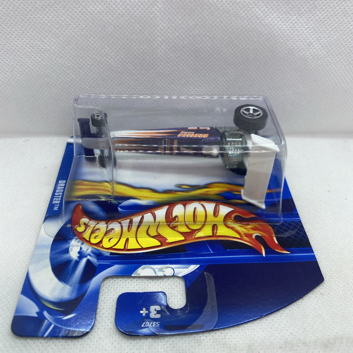 Die-cast dragster in clear blister on blue-and-flame Hot Wheels card, top view.