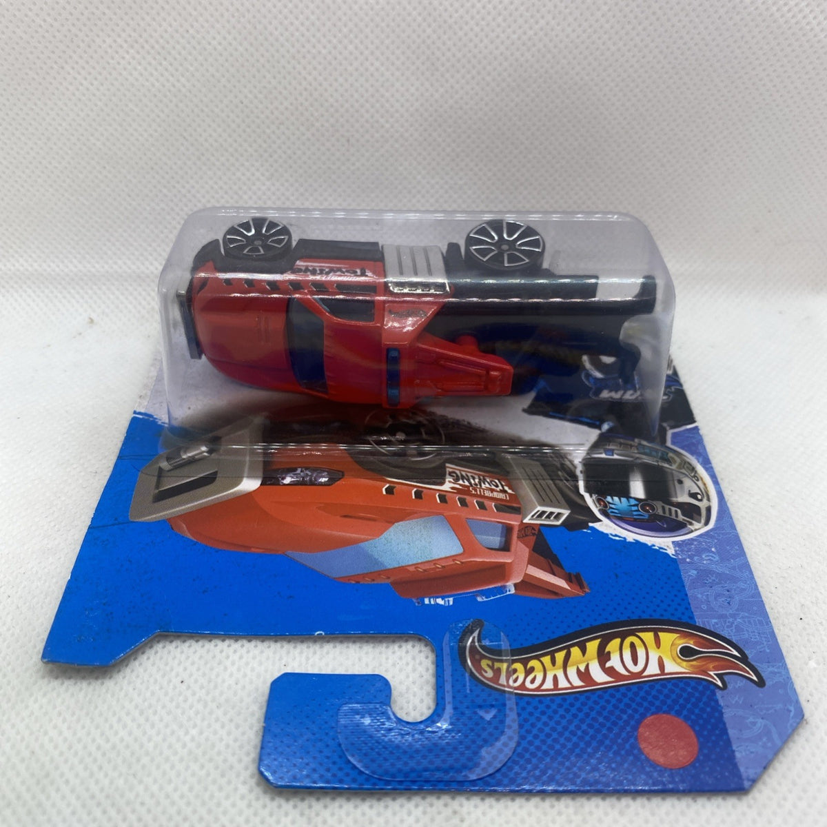 Orange and red die-cast tow truck in clear blister pack on Hot Wheels card.