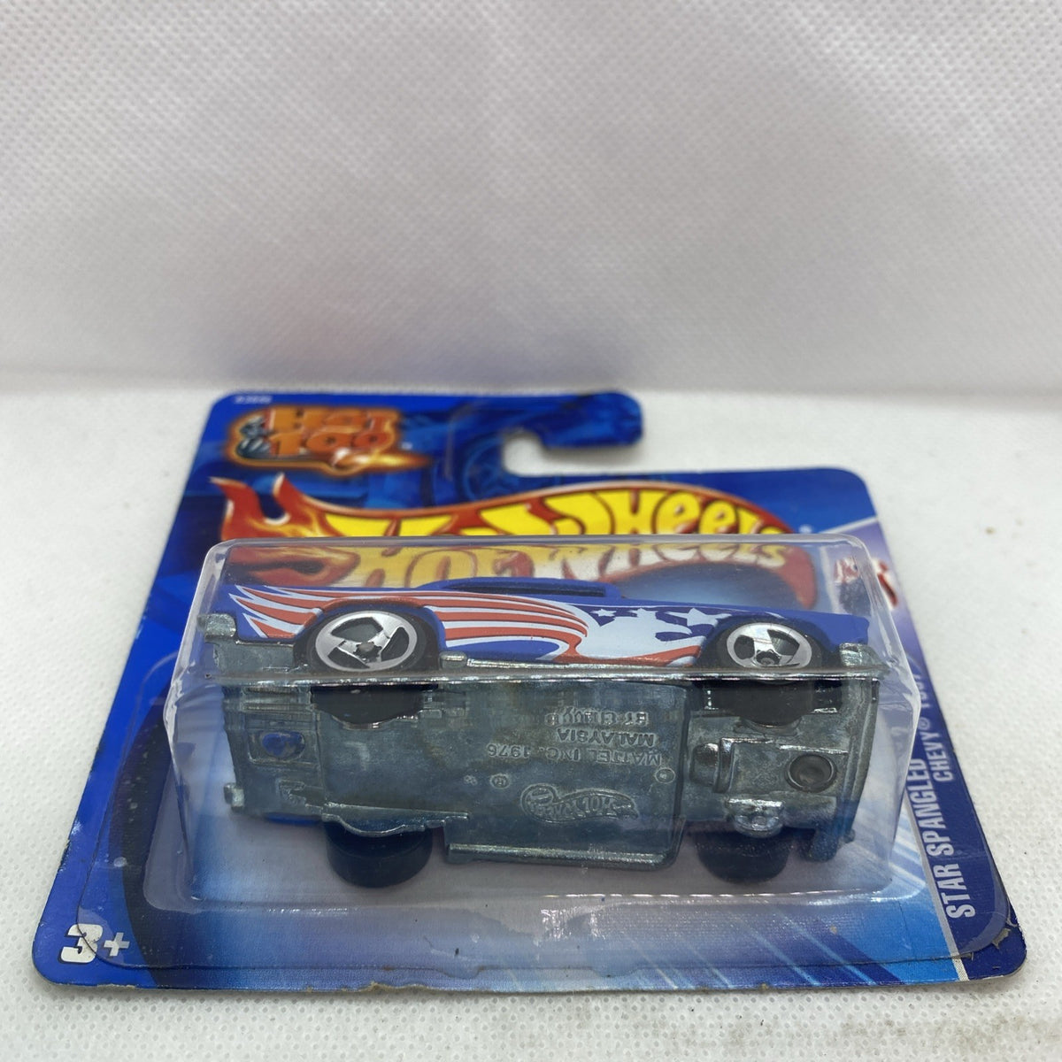 Die-cast car in blister pack, side view with blue body, red flame stripe, silver wheels