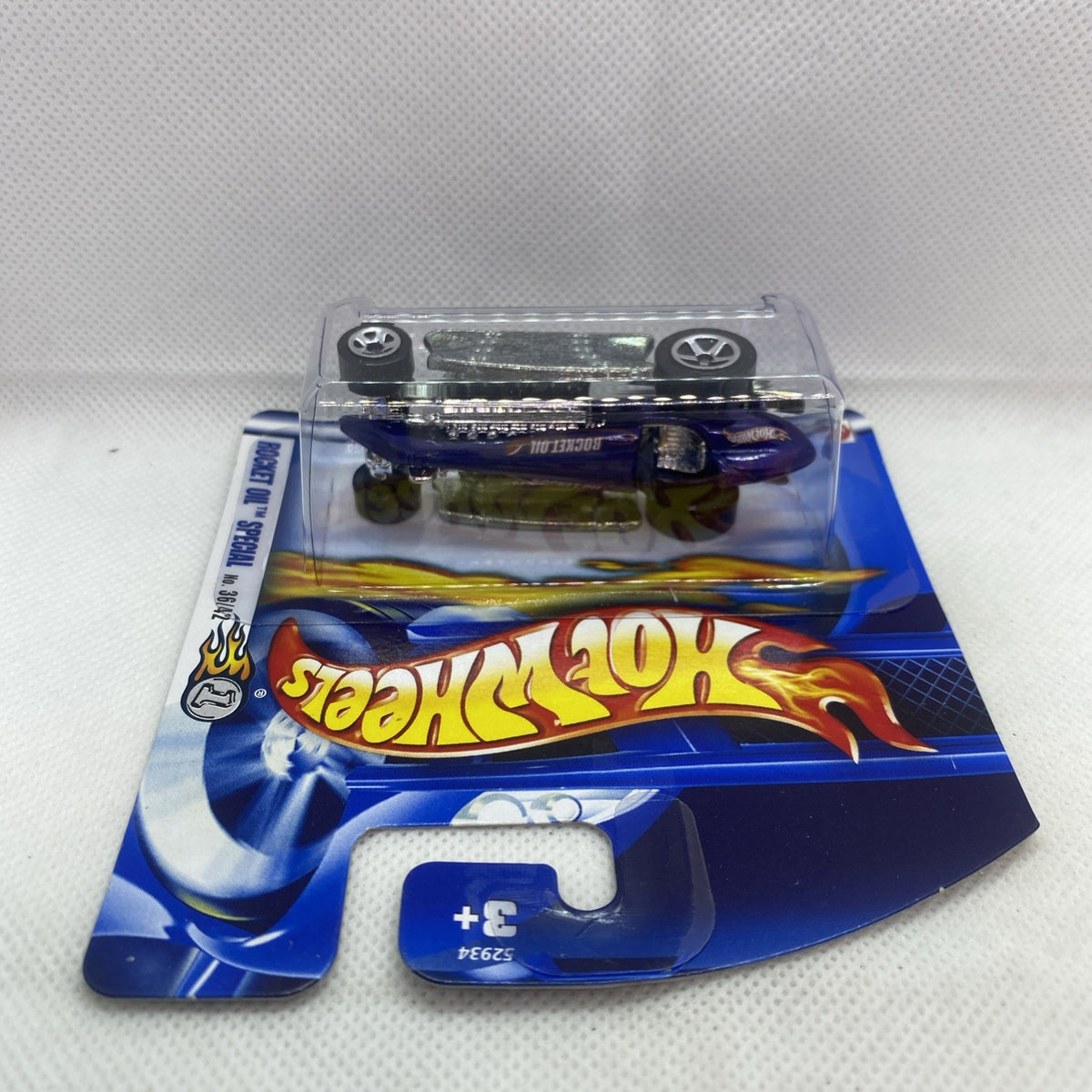 Hot rod die-cast in clear top blister window on Rocket Oil themed Hot Wheels card