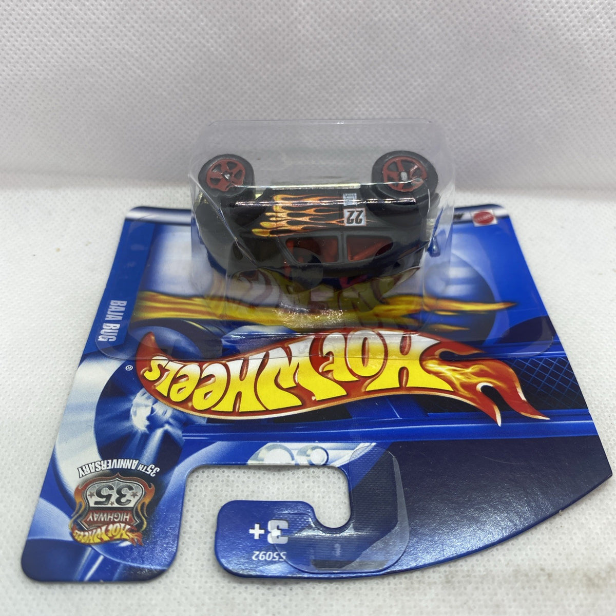 Die-cast toy car blister pack, black car with flame decals, wheels visible through plastic.