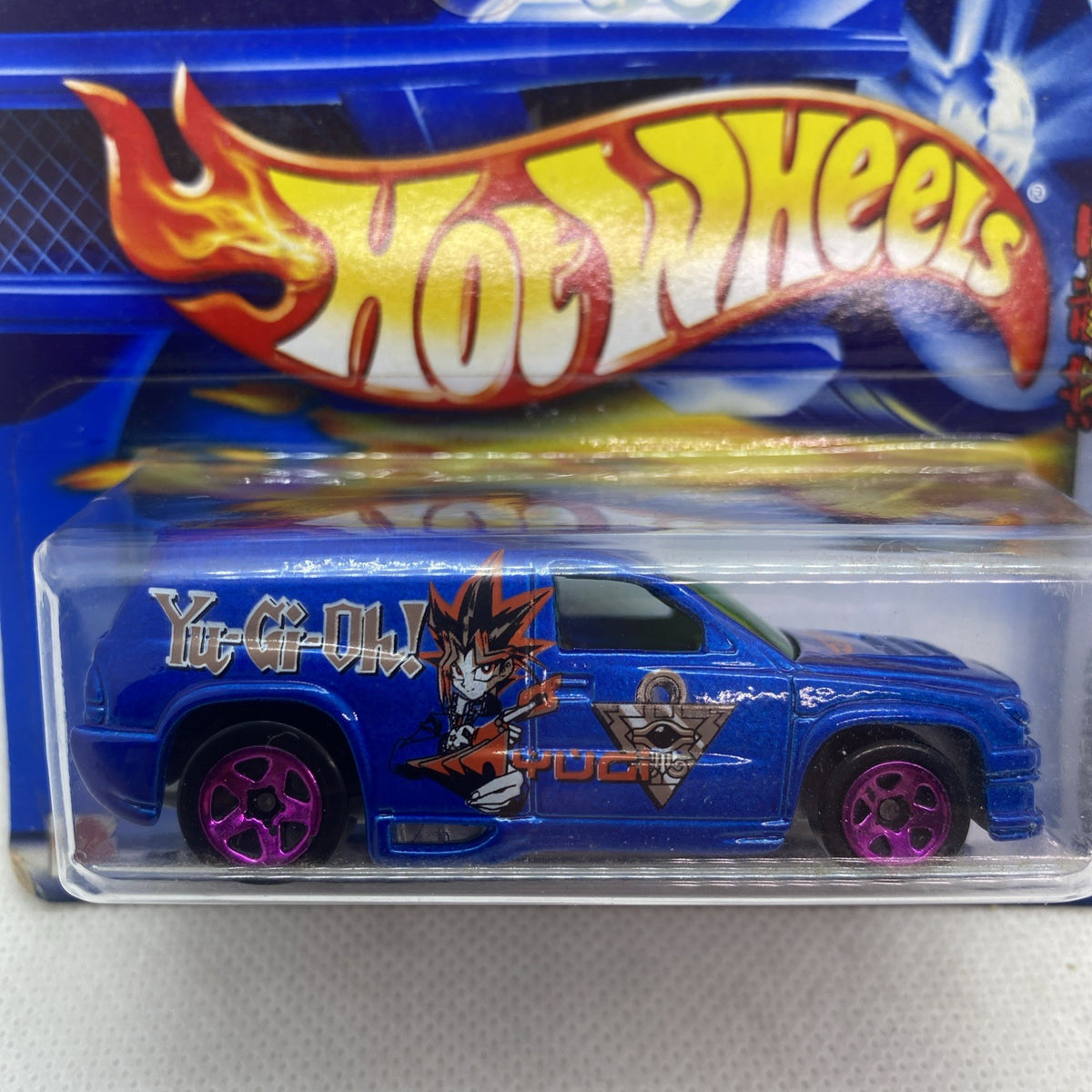 Blue Hot Wheels truck with Yu-Gi-Oh graphics, purple wheels, in clear blister.